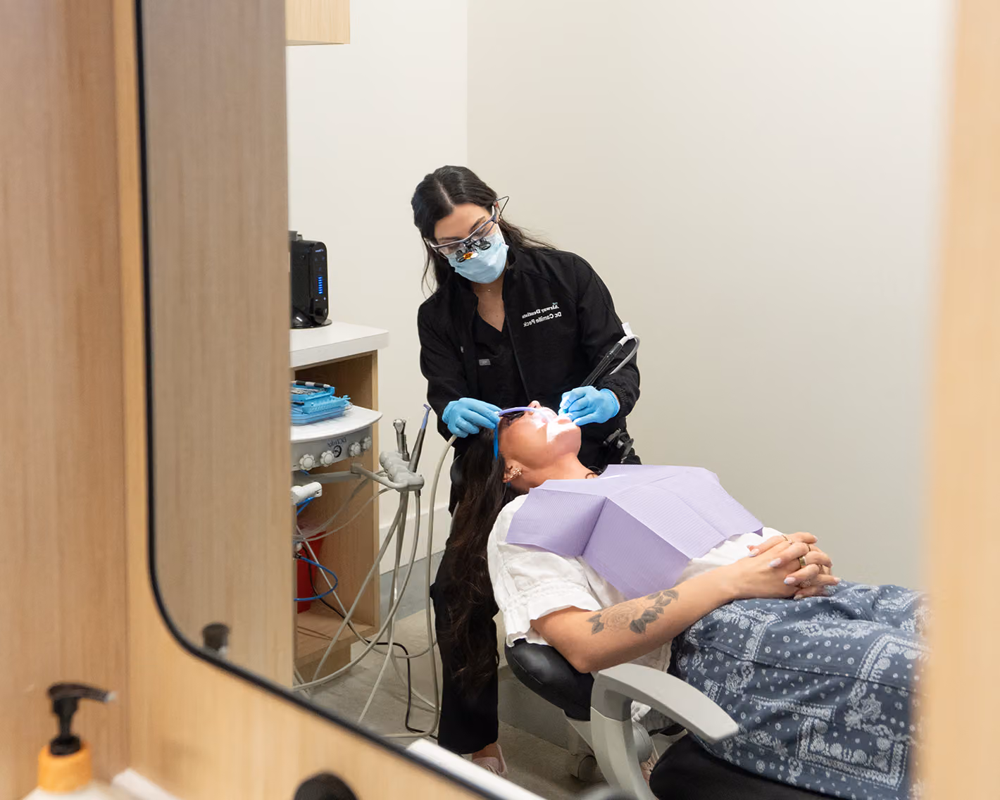 Dentist working with dental instruments during a tooth-colored filling procedure.