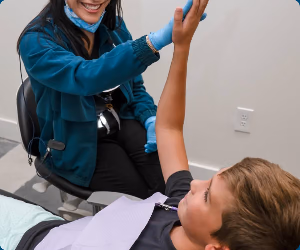 A dental team member smiles with a child patient during a relaxed dental visit.