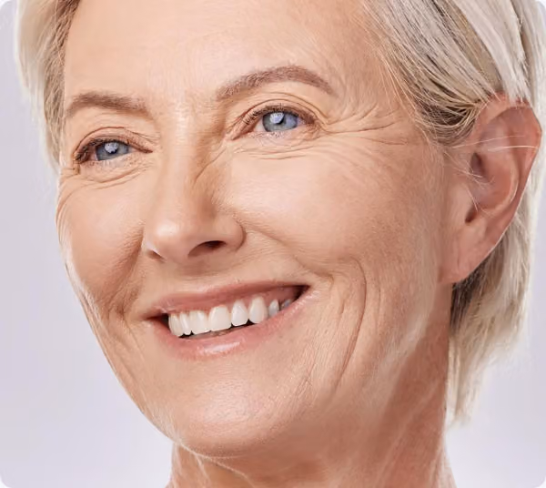 Smiling older woman showing natural-looking metal-free crowns.