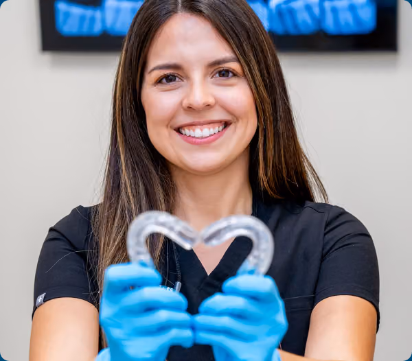 Airway Dentists clinician smiling while holding a clear orthodontic appliance.