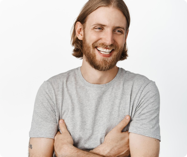 A smiling adult man in a gray T-shirt stands with his arms crossed.