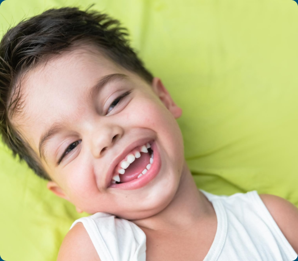 Smiling young boy in a white tank top resting on a yellow background.