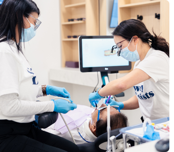 Dentist working with dental instruments during a tooth-colored filling procedure.