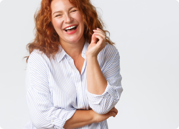 Smiling adult woman with red hair wearing a white striped shirt.