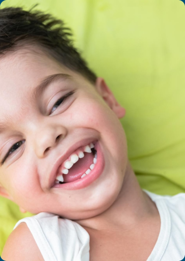 Young child laughing on a green pillow, illustrating early childhood development.