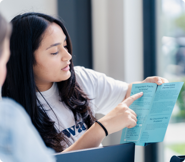 Young woman reading a Dental Savings Plan brochure during a consultation visit.