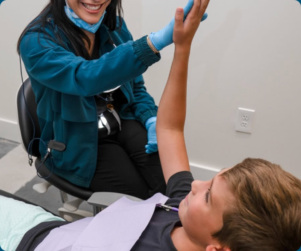 A dental team member smiles with a child patient during a relaxed dental visit.