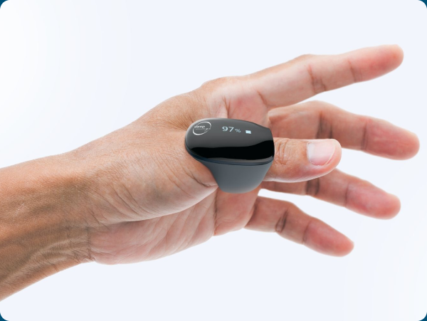 A hand holding the small black SleepImage sensor ring against a soft background.
