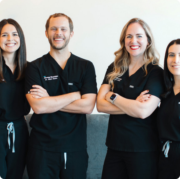 Four members of The Airway Dentists team in dark scrubs, standing together with crossed arms and warm smiles.