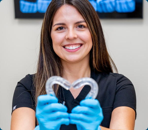 Airway Dentists clinician smiling while holding a clear orthodontic appliance.