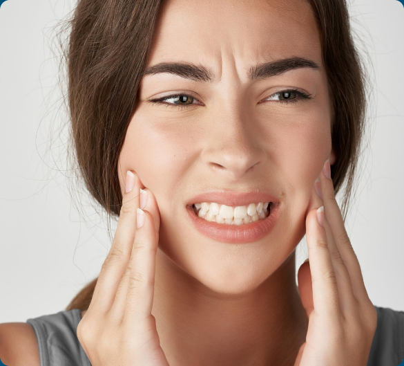 Woman touching her cheeks with both hands, displaying a pained expression that suggests jaw or facial discomfort.