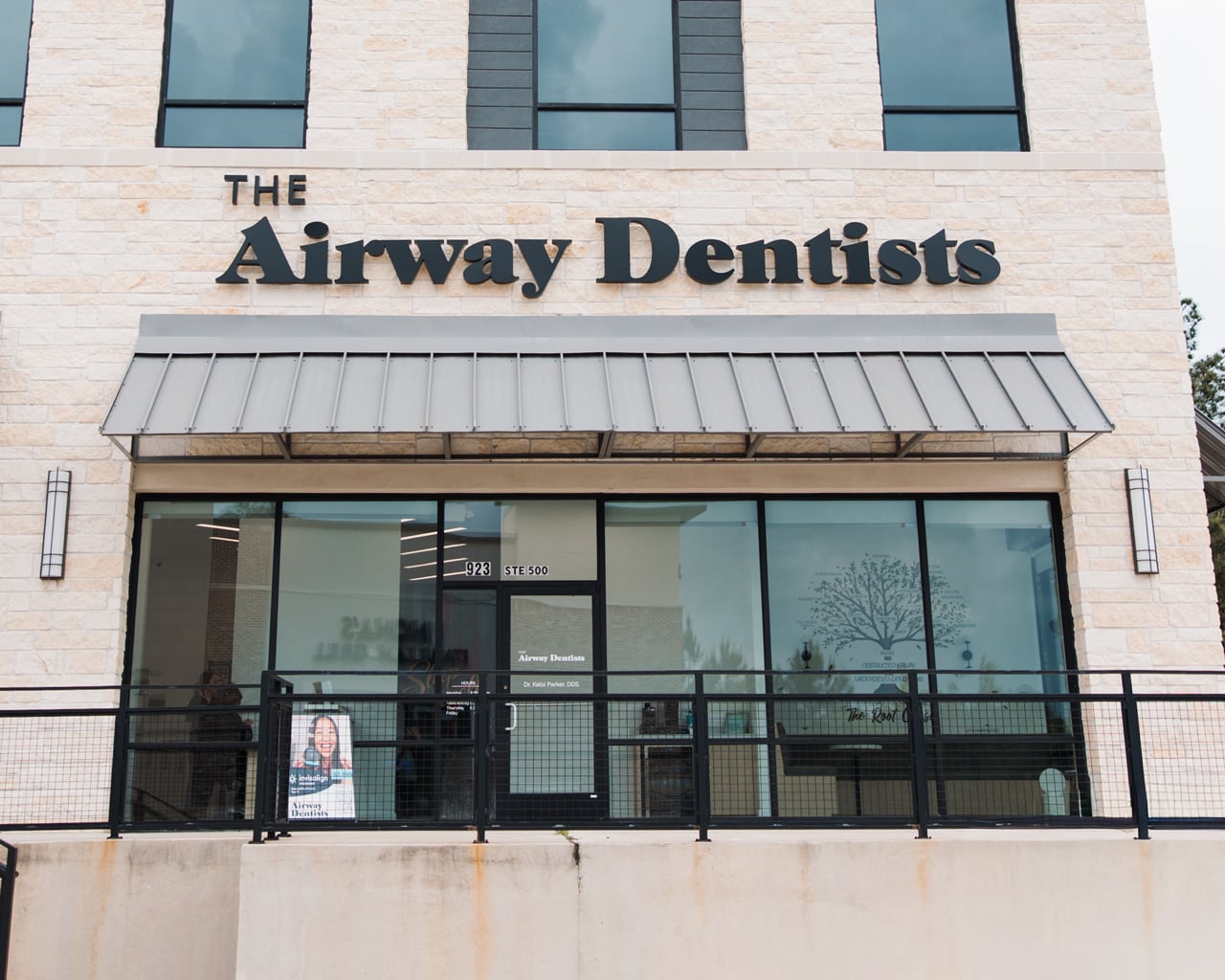 The exterior of a building with a sign reading "The Airway Dentists" above a glass entrance door and windows.