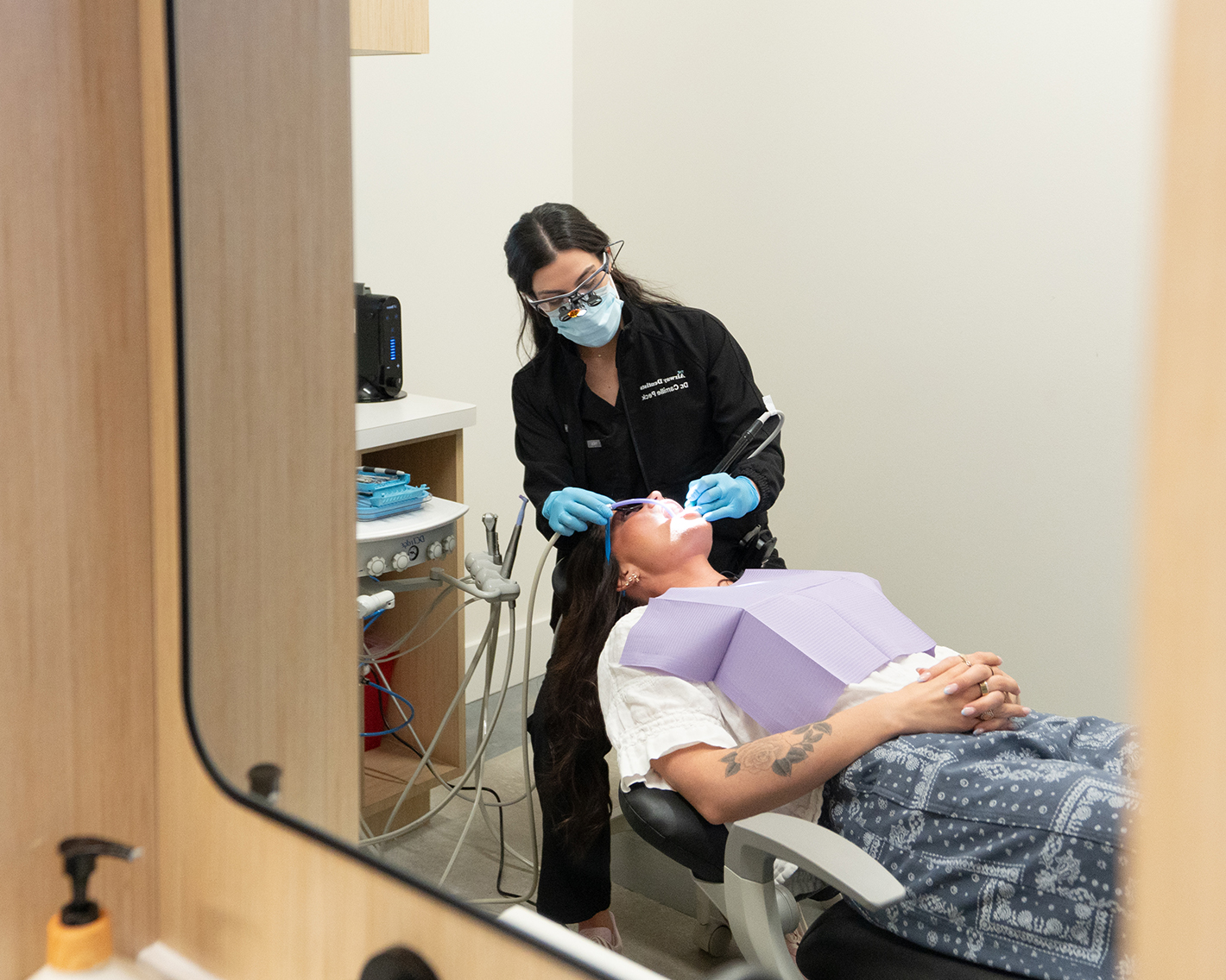 Dentist working with dental instruments during a tooth-colored filling procedure.