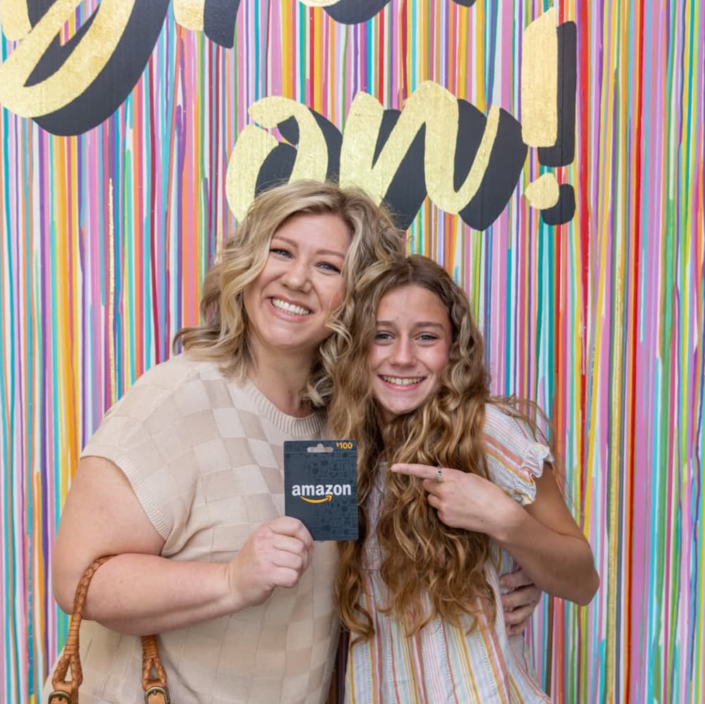 Smiling mother and child at The Airway Dentists, holding a gift card