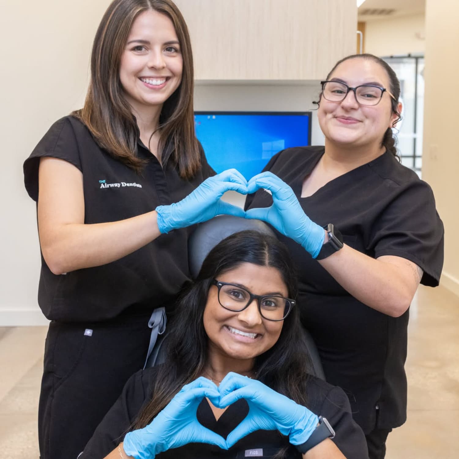 The Airway Dentists staff and doctors, smiling and making heart shapes with their hands