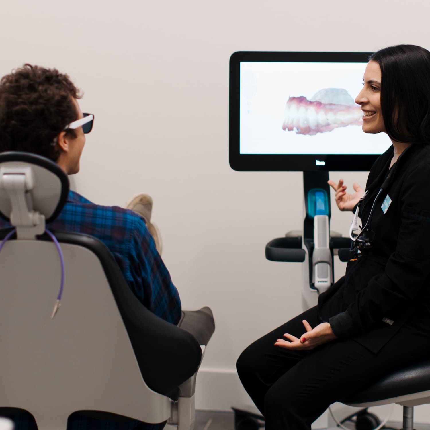 Dr. Camille Peck sitting with a patient in a treatment room, reviewing dental imaging