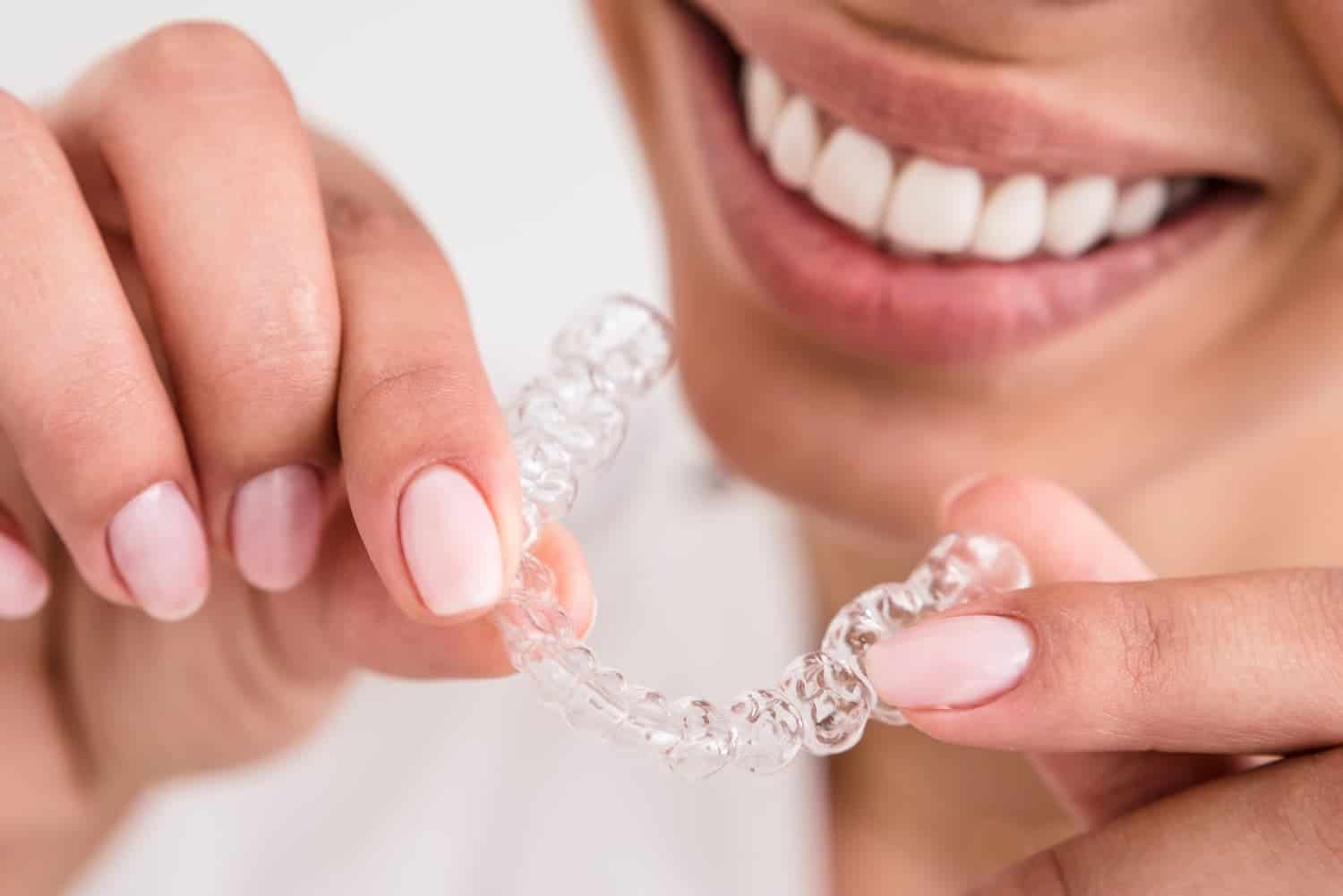 smiling woman holding an Invisalign tray