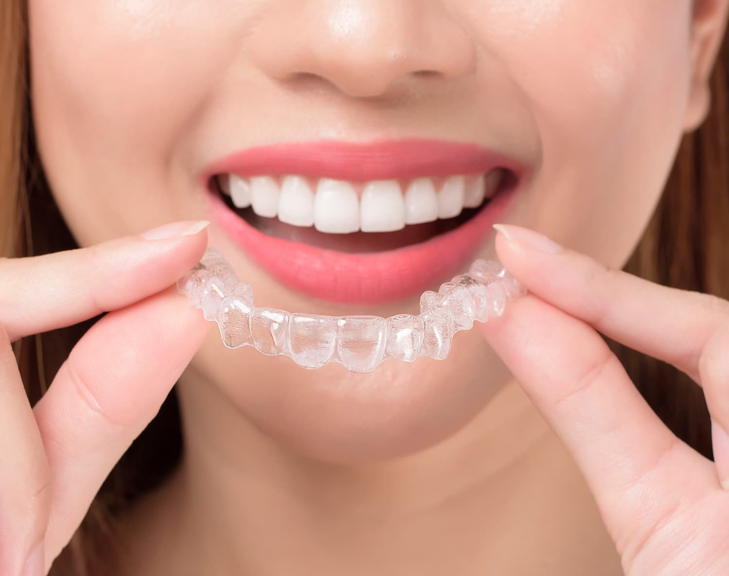 smiling woman holding an Invisalign tray